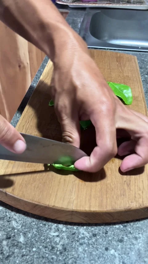 4K Close Up Of A Man's Hand Slicing Citrus Leaf On The Wooden Board With Kni Stockbeeldmateriaal 337226243