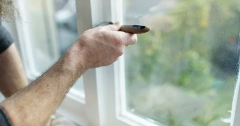4K Close up of mature bearded man painting indoor window frames with white paint Stock Footage 88221545