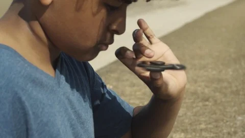 4K Close Up of Mixed Race Young Boy Spinning Toy on Thumb 库存影片 75956234