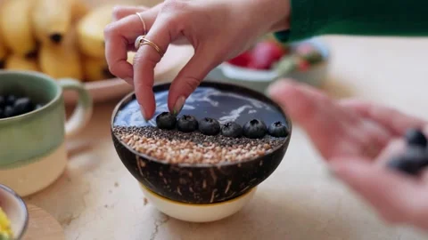 4K Close-up Person Preparing Blueberry Smoothie Bowl in Coconut Shell Video stock 330480698
