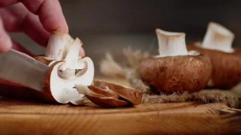 4K Close-up Person Using Knife to Cut Cremini Mushrooms on Cutting Board Stock Footage 330480734