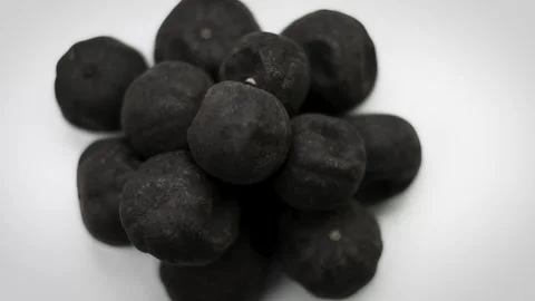 4K Close-Up Pile Black Dried Limes Loomi Variation on White Background Stock Footage 336661342