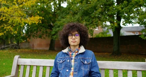 4K Close up portrait of serious young man sitting on park bench, staring at came Stock Footage 87161004
