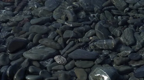 4K close up of sea pebbles with light dancing on water Stock Footage 56701240