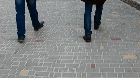 4K Close up shot of two pairs of feet walking along paving stone blocks. Stock-Footage 99932672