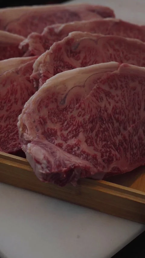 4K close up stack of wagyu beef steaks in wood platter - vertical video Stock Footage 315123506