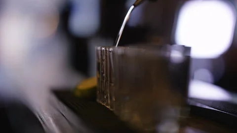4K Close Up Of Unrecognizable Barman Pouring Alcohol Into Row Of Shot Glasses Stock Footage