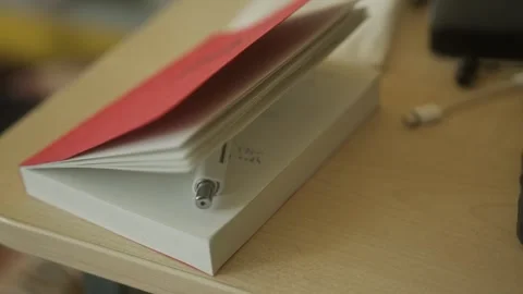 4K Close-Up video of slightly  Open Notebook with Pen on Desk in Cinematic Light Stock Footage 307129288