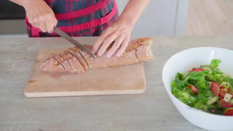 4K close-up video of woman’s hands cutting fresh baked bread in cozy kitchen, pr Video stock 314748021