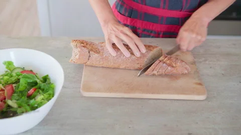 4K close-up video of woman’s hands cutting fresh baked bread in cozy kitchen, pr 스톡 동영상 327214595