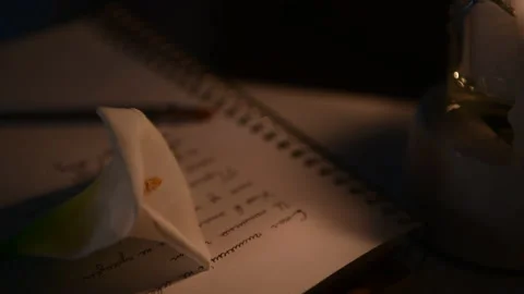 4k Close up of white calla lilly and notebook with text on the candlelights Stock Footage 156757878