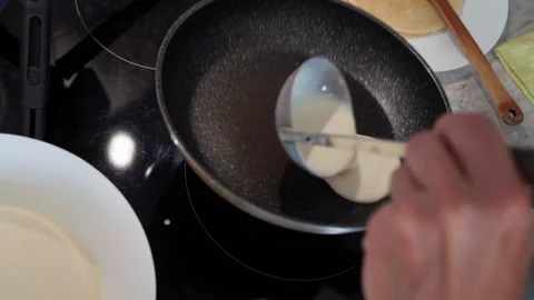4K close-up of woman’s hands pouring liquid pancake dough while frying on electr Video stock 325223405