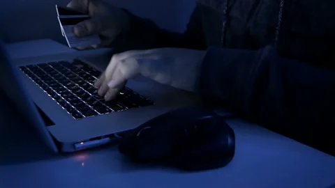 4k closeup footage of hacker holding credit cards typing code on laptop Stockbeeldmateriaal 88917811