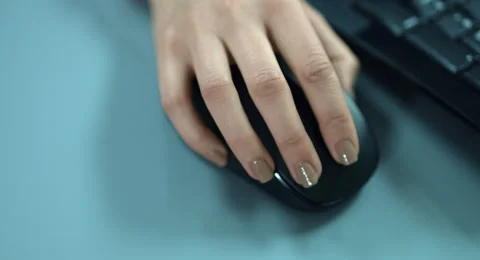 4K: A closeup view from a moving woman hand at a computer mouse. Stock Footage