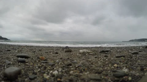 4K Cloudy skies over pebbly beach, tide coming in, closeup of sand and stones Stockbeeldmateriaal 47201055