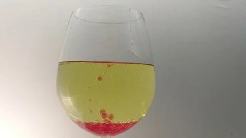 4K Coloring Drops Falling In Wineglass With Sunflower Seed Oil &amp; Water Emulsion Stock Footage 83598172