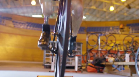 4K Competitive cyclist with prosthetic leg, practicing with trainer in velodrome Stock Footage