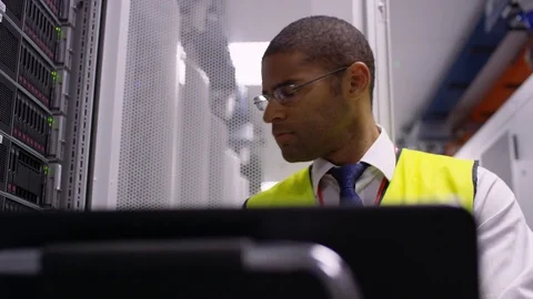 4K Computer engineer carrying out checks in a data center server room Stock Footage
