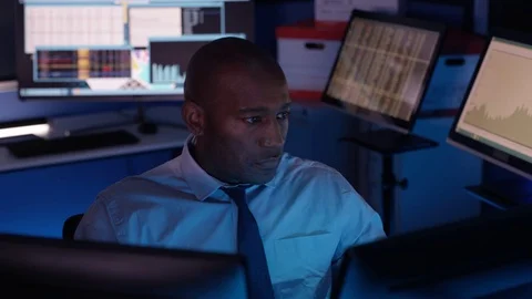 4K Computer expert working in a dark room surrounded by computer screens Stock Footage 73411876