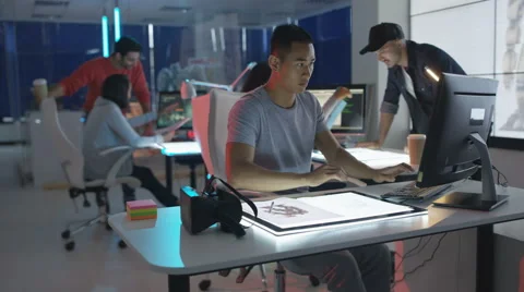 4K Computer game designer working at his desk &amp; looking into VR viewer Stock Footage 67903743
