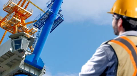 4K Construction Worker in Foreground Looking up at Industrial Crane Stock Footage 58480618