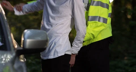 4K Cop handcuffing young man &amp; putting him in the back of the patrol car Stock Footage 113655483