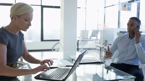 4K Corporate businesswoman working on laptop in office & man talking on phone Stock Footage