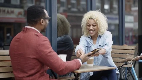 4K Couple Chatting &amp; Looking At Computer Tablet At Outdoor Cafe Table In City Stock Footage 75679268