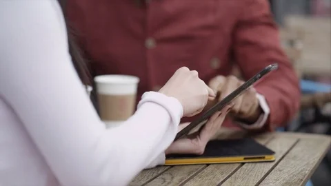 4K Couple Chatting &amp; Looking At Computer Tablet At Outdoor Cafe Table In City Stock Footage 75681863