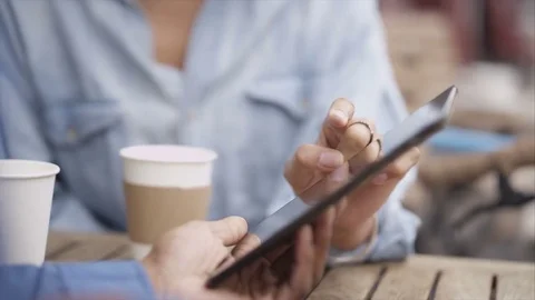 4K Couple Chatting &amp; Looking At Computer Tablet At Outdoor Cafe Table In City Stock Footage 75713224