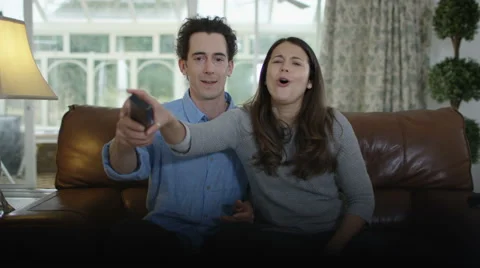 4K Couple fighting over the remote control in front of TV Stock Footage 67865285