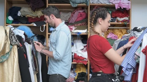 4K couple of friends checking clothes rack in vintage shop doing okay winking Stock Footage 90800854