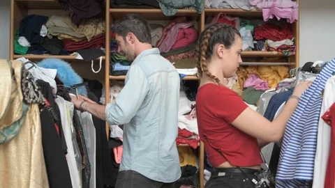 4K couple of friends checking clothes rack in vintage shop doing okay winking Stock Footage 90801799
