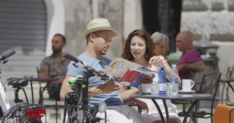 4K Couple looking at map at outdoor cafe table in the city. Stock Footage 68774945