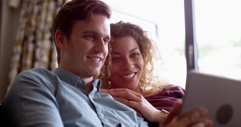 4K Couple relaxing on sofa, watching funny tv show or movie on digital tablet Stock Footage 114658162