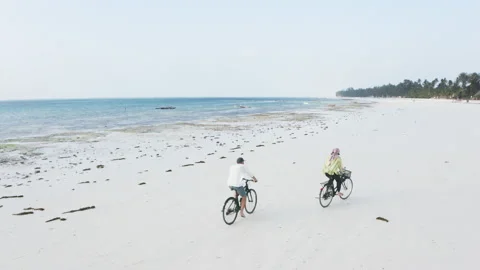 4K Couple riding bicycles on empty beach near ocean in Zanzibar drone video Stock-Footage 157908148
