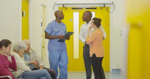 4K Couple talking to doctor &amp; getting good news in hospital waiting area Stock Footage 63018682
