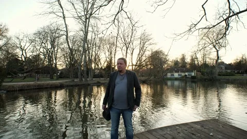 [4k] Crane shot down to goatee man putting of his head in front of sunset Video stock 152050431