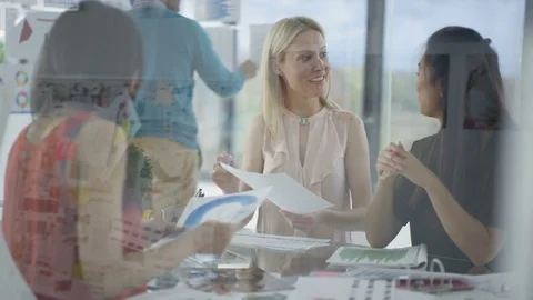 4K Creative business team looking at photos &amp; printed graphs in a meeting Stock Footage 76033084