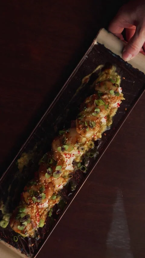 4K creative scallop sushi roll plate pulled by hand on table - vertical video Stock Footage 315123360