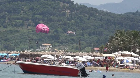 4K Crowded Sidari beach in Corfu Island people enjoy paragliding sport kids play Stock Footage 78772910
