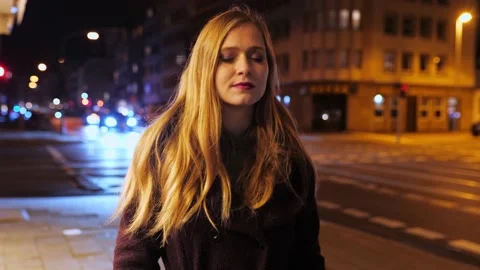 [4k] cute young blonde woman going for a walk on a street at night Stock Footage
