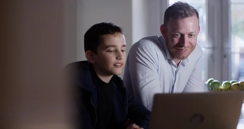 4K Dad &amp; son watching video content on laptop, laughing &amp; reacting to what they  Stock Footage 107600363