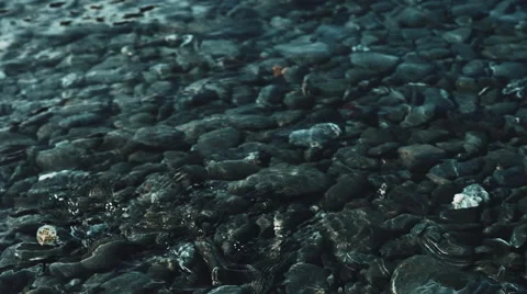 4K dark dramatic footage of waves rolling in over a pebble beach Stock Footage 51355153