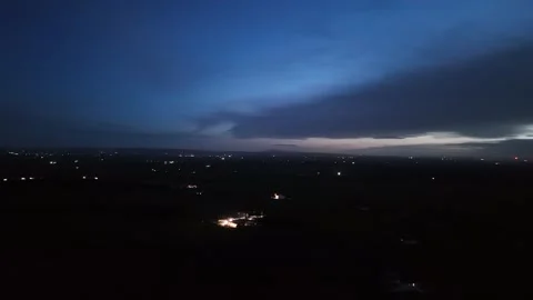 4K Dark Landscape with Distant Lights Under Dramatic Cloudy Sky Stockbeeldmateriaal 332802722