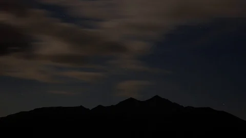 4k darkened star time lapse with clouds moving fast and moon entering frame Video stock 96305576