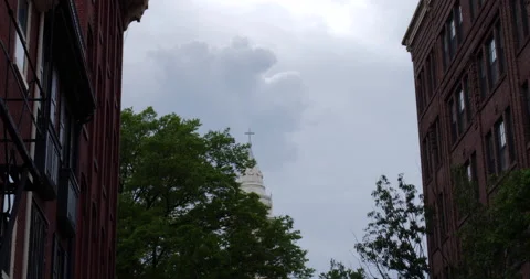 4K DAY TIMELAPSE OF CLOUDY SKY WITH CHURCH STEEPLE BETWEEN TWO BUILDINGS Stock Footage 132080904