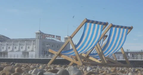 4K | Deck Chairs on Beach in front of Brighton pier Stock Footage 47715950