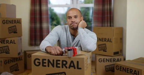 4K Depressed man packing boxes for house move, unhappy to be leaving his home Stock Footage 85514784