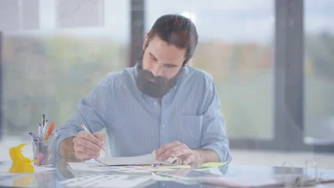 4K Designer working at his desk takes a break to turn &amp; look out of the window Video stock 76055560